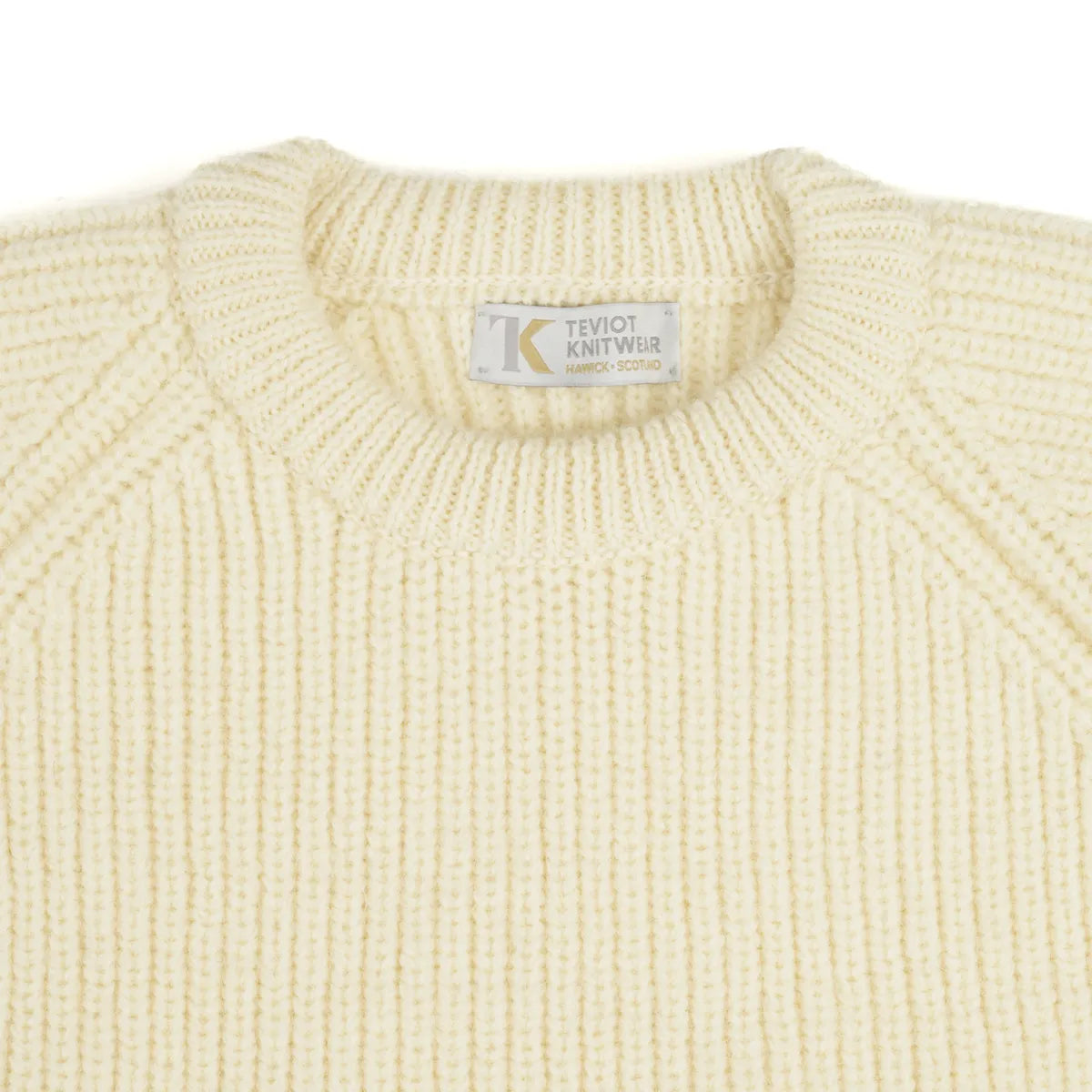 Close-up of a cream coloured ribbed knit crew neck sweater with a visible Teviot Knitwear label at the collar.